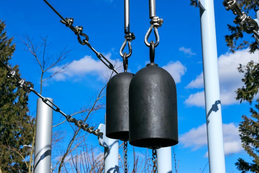 Close Up Of Black Metal Bells Against A Cloudy Sky