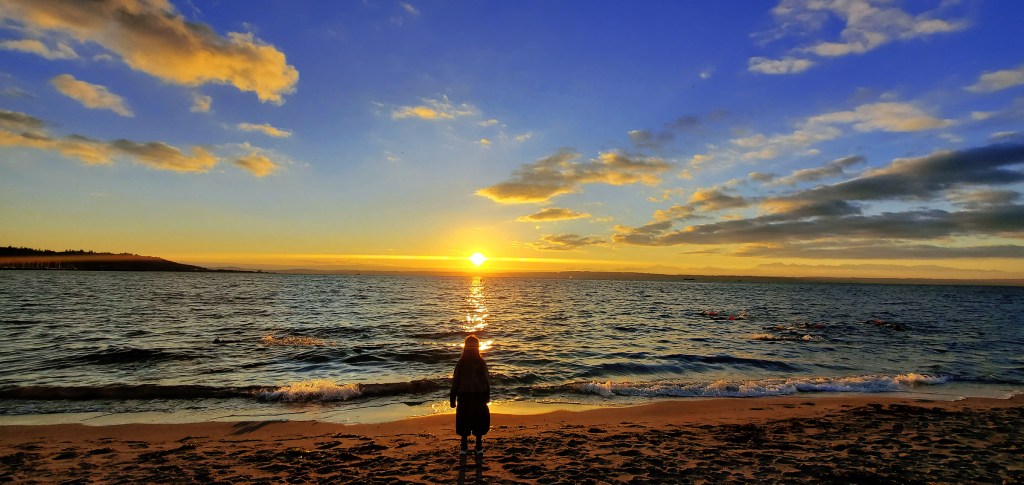Little Girl Looking At An Orange Sunset At The Beach